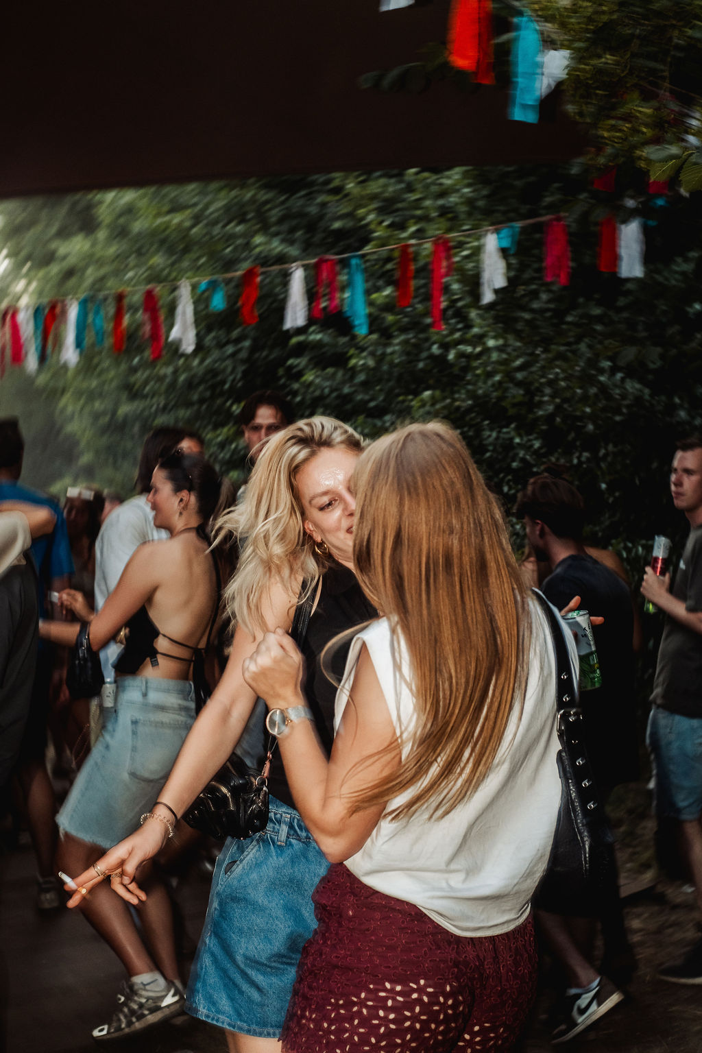Twee vrouwen die elkaar omhelzen op een festivalterrein onder vlaggetjes