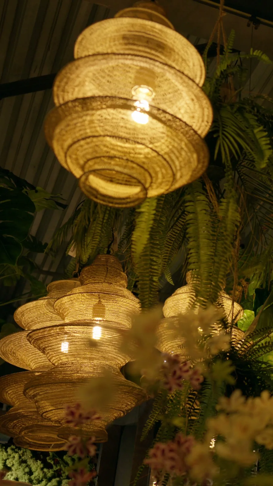 Gouden gevlochten hanglampen tussen varens en gele bloemen, still uit een staande reel