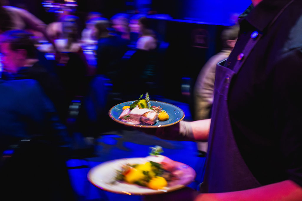 Een ober draagt borden door een volle zaal