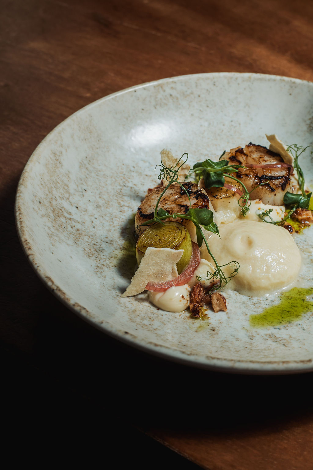 Bord met coquilles, prei en schuim op een houten tafel
